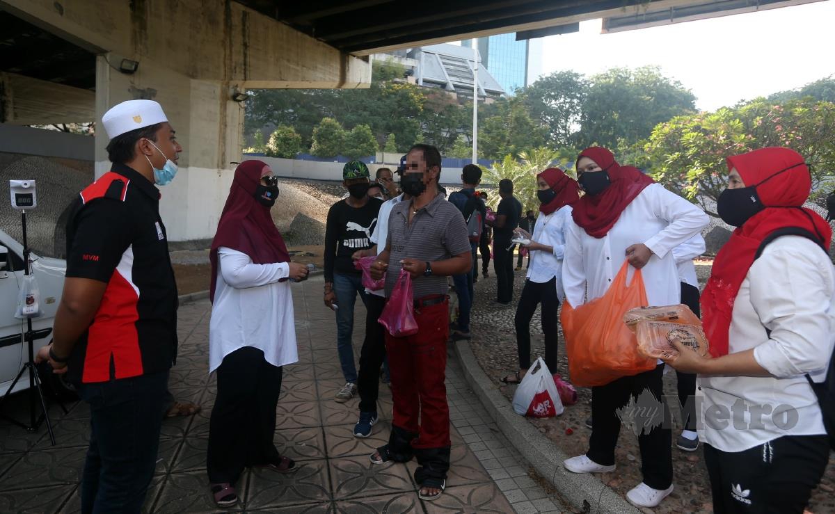 MUHAMMAD Hasbullah (kiri) dan Haliza (dua dari kiri) bertanya khabar gelandangan ketika menyampaikan pek makanan di Bulatan Jalan Kinabalu, Kuala Lumpur, hari ini. FOTO HAIRUL ANUAR RAHIM
