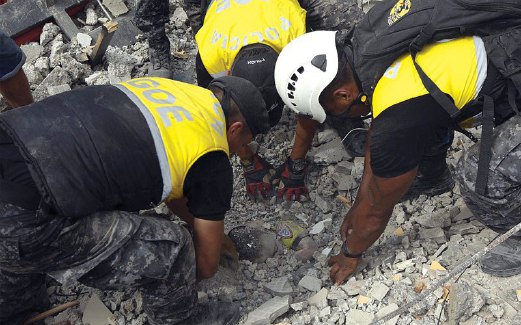 PASUKAN penyelamat berusaha mengeluarkan mayat seorang kanak-kanak dari runtuhan bangunan di Ecuador.