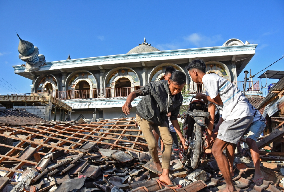 PENDUDUK mengeluarkan motosikal dari runtuhan bangunan di Gunungsari Lombok Barat. FOTO Reuters/Antara Foto 