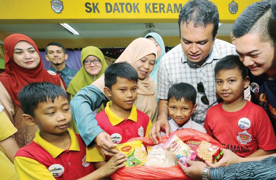 MUHAMMAD, Pengurus Empire Projek Mohd Ashraff Khan Najib (kanan) dan Siti Zaharah melihat bungkusan makanan diterima murid.