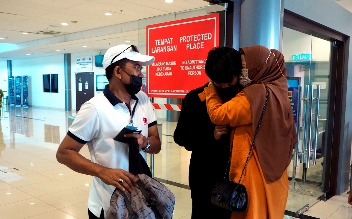 MAS Rika (kanan) ditemani suami, Siyatno Harun, 52, (kiri) memeluk anak sulungnya, Syafiq Aditya Ababil, 22, yang tiba di Kompleks Imigresen, Kastam, Kuarantin dan Keselamatan (ICQS) Kota Laksamana, Melaka. FOTO BERNAMA