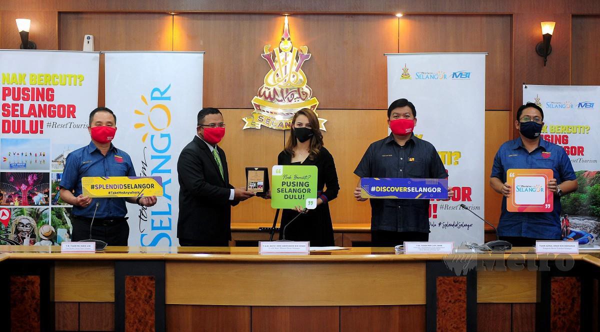 AMIRUDIN (dua dari kiri) menyampaikan cenderahati kepada Juliana Evans (tiga dari kanan) yang dilantik sebagai duta Kempen "Nak Bercuti? Pusing Selangor Dulu!" pada majlis pelancaran yang berlangsung di Bangunan Setiausaha Kerajaan Negeri Selangor hari ini. FOTO BERNAMA