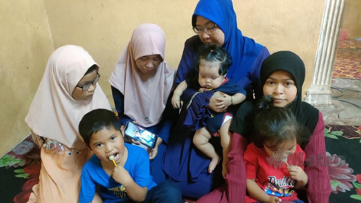 Zaleha (baju biru) bersama enam anaknya melihat gambar suaminya yang meninggal dunia akibat tertimbus tanah runtuh di tapak pembinaan Jalan Padang Tembak, Bukit Pinang. FOTO ZULIATY ZULKIFFLI