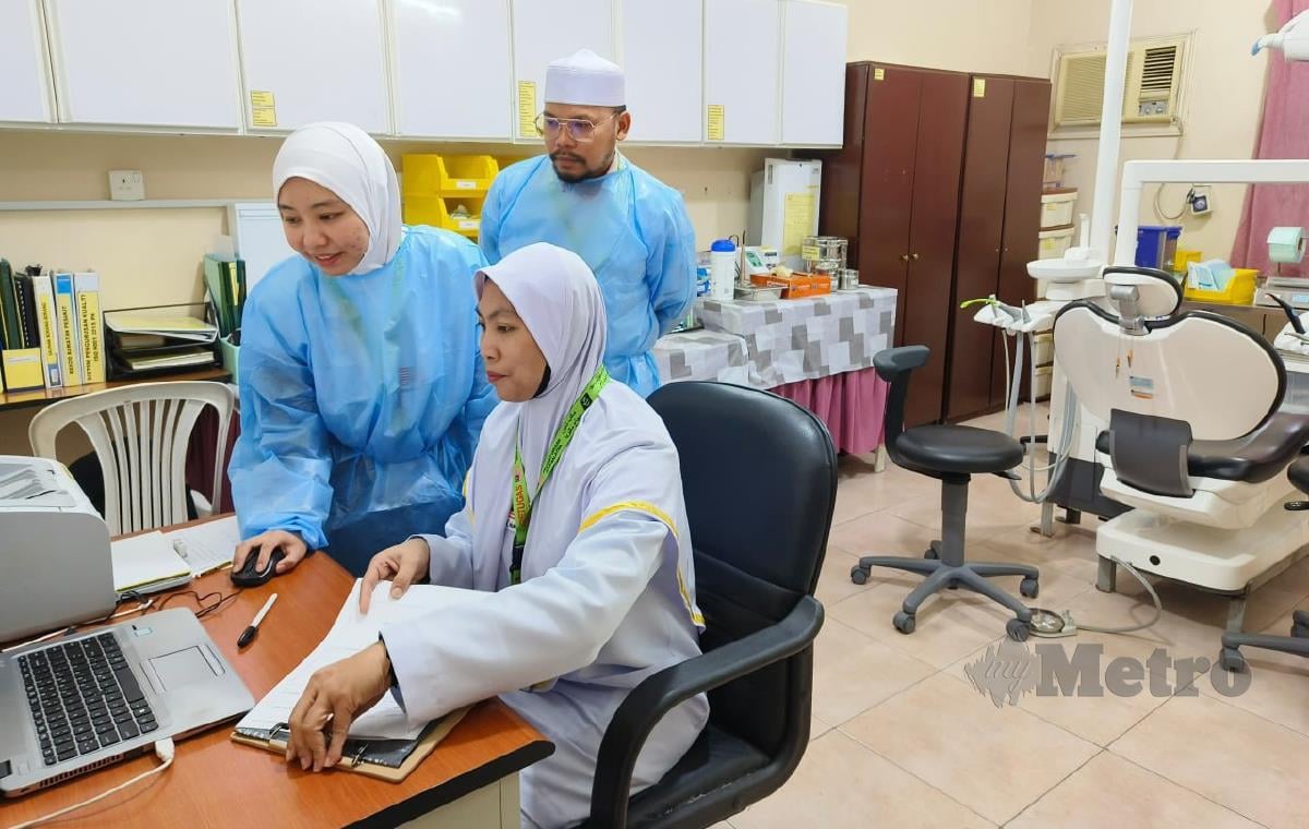 Dr Siti Umairah sedang menyemak rekod pesakit sambil dibantu Juruterapi Pergigian, Nur Syuhana Samsudin dan Pembantu Pembedahan Pergigian, Meor Al Hafiz Meor Abd Halim di kliniknya, baru-baru ini.