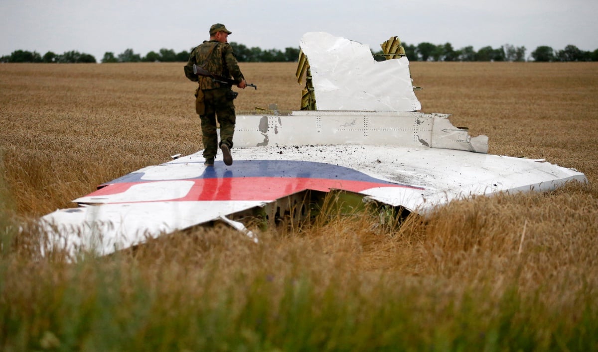 Anggota pemisah Rusia berdiri di atas serpihan pesawat MH17. - FOTO Reuters