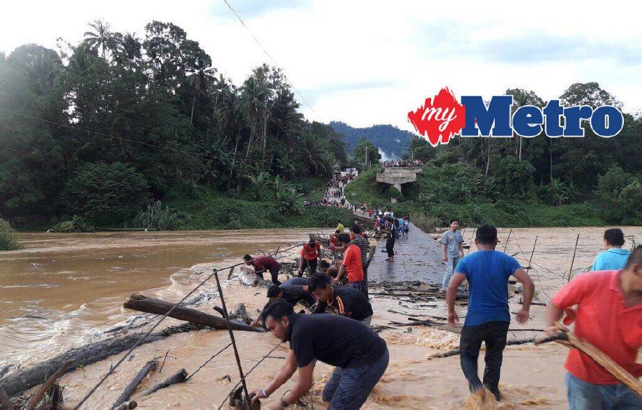 Penduduk bergotong-royong membuang sisa kayu yang tersekat di jambatan sementara merentasi Sungai Nenggiri dekat Kampung Pulau Setelu, Gua Musang. FOTO Ramli Ibrahim