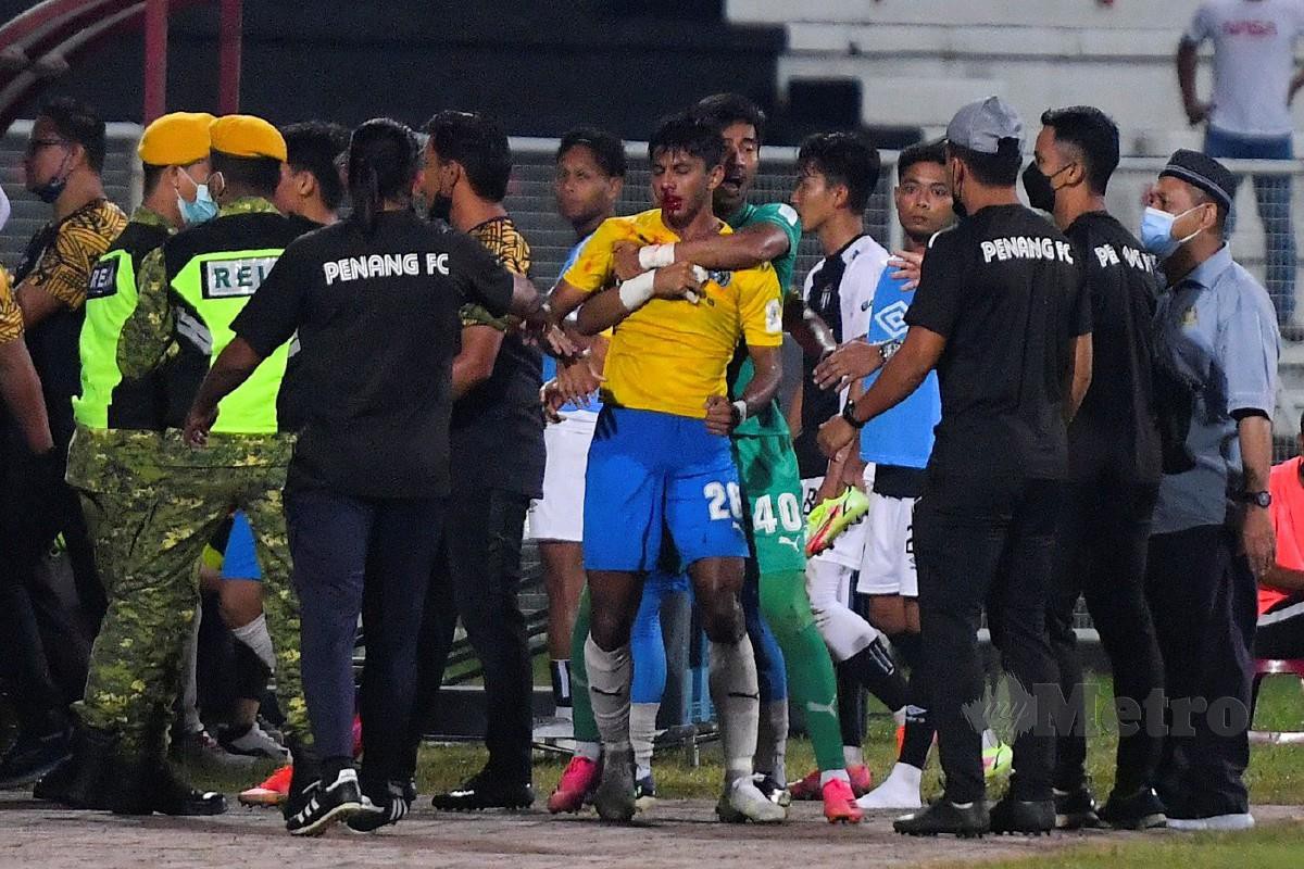 PENJAGA Penang FC, Shafiq Afifi Suhaimi (enam kanan) menenangkan rakannya, Adib (tujuh kanan) yang cedera di muka ketika suasana tegang antara pemain TFC II dan Penang FC. FOTO Bernama