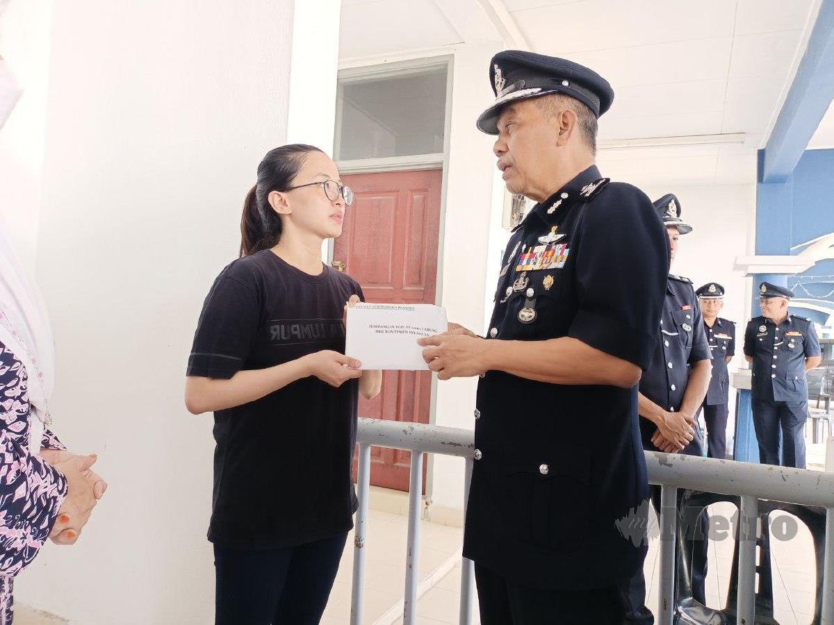 JIA Ying menerima sumbangan daripada Azman di perumahan polis Kampung Terbak. FOTO Siti Rohana Idris