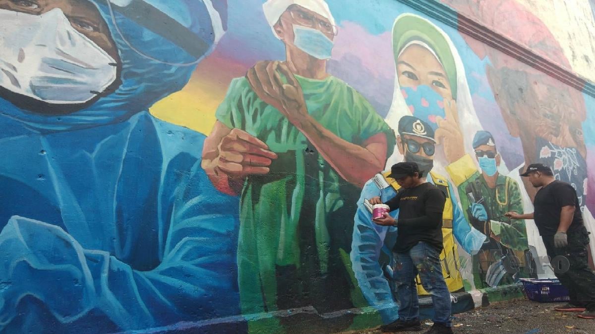 MOHAMAD Sayuti Rosli bersama rakannya menyiapkan mural. FOTO SYAHERAH MUSTAFA