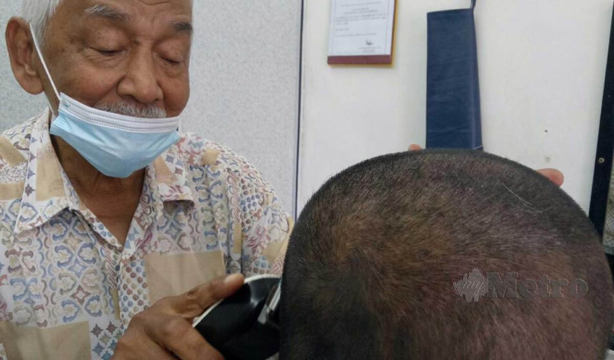 TUKANG gunting rambut, Yunos mencukur rambut pelanggan dipremisnya di Jalan Aji Segamat. FOTO Ahmad Ismail