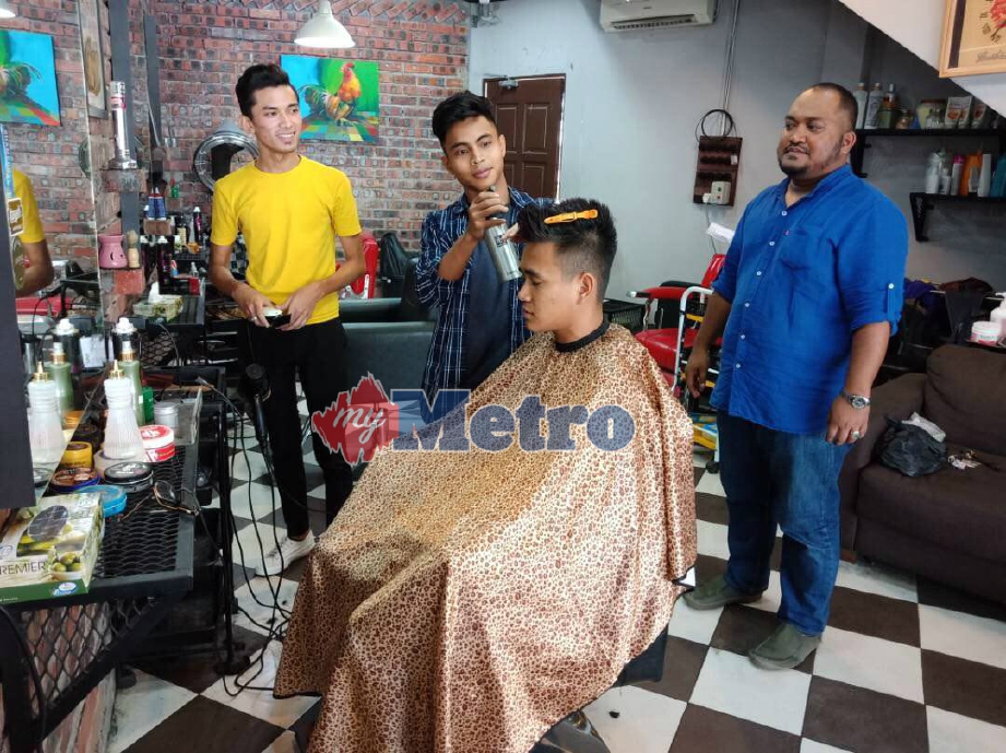 MOHD Rosli (kanan) melihat Shahrul Ikhwan memotong rambut pelanggannya, disertai Shahrul Nizam Azahar, 18, (kiri). FOTO/ Mohamad Zulhairie Manzaidi