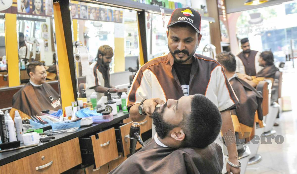 TUKANG gunting dari India menggunting rambut pelanggan ketika tinjauan di Brickfields, Kuala Lumpur. - FOTO Aizuddin Saad