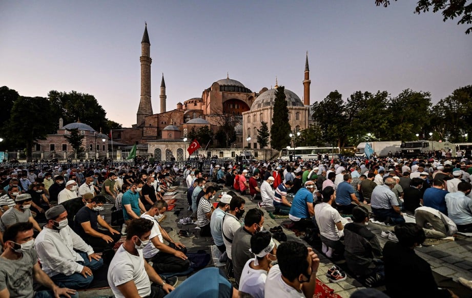 PENDUDUK Turki berkumpul di luar Hagia Sophia dan menunaikan solat selepas monumen itu diisytihar sebagai masjid semula pada Jumaat. FOTO AFP.