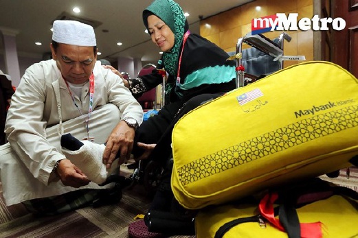 MOHAMAD Supian Sapar, 57, membalut kaki isterinya, Normah Ab Majid, di Kompleks Tabung Haji Kelana Jaya. FOTO Abdullah Yusof