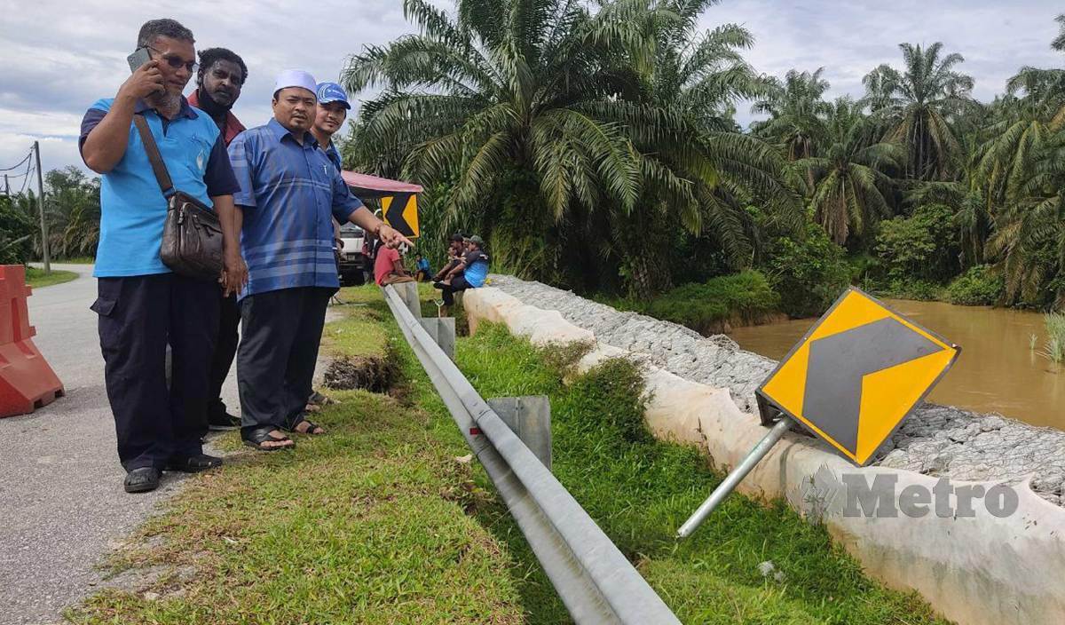 ZULFADLI (kanan) menunjukkan kawasan hakisan tebing sungai yang menyebabkan saluran paip bekalan air rosak berhampiran Kilometer 3 Jalan Kampung Kuala Slim - Slim River. FOTO Rosman Shamsudin
