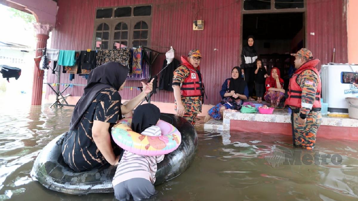 JAINAL @ Zainal Madasin (tengah) melakukan tinjauan di rumah yang digenangi banjir bagi memastikan keselamatan penghuni di Kampung Padang Licin. FOTO NIK ABDULLAH NIK OMAR