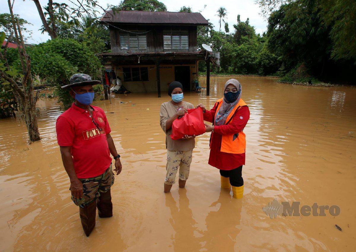 HALIMATON (kanan) menyerahkan bantuan kepada mangsa banjir Mariani Saad di Kampung Sungai Petani. FOTO DANIAL SAAD