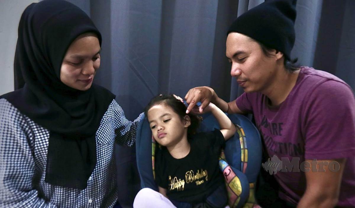 MOHD Azroy (kanan) dan isteri, Nur’aidah (kiri) melihat anaknya, Hana Raissa yang menghidap autisme dan epilepsi (sawan) ketika ditemui di Kampung Lembah Jaya Selatan, Ampang. FOTO Azhar Ramli