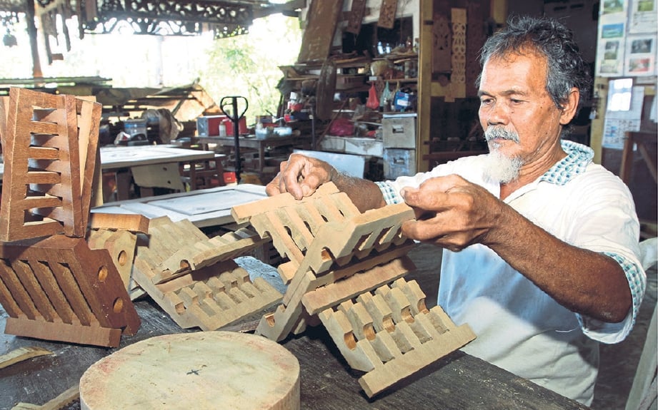 MUHAMMAD menghasilkan pelbagai kraftangan berasaskan kayu di bengkelnya di Kampung Chendor Sempadan, Kuantan.