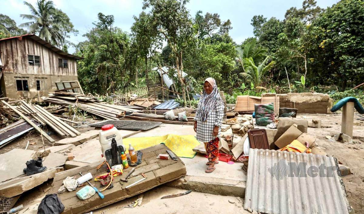 ROBIAH  membersihkan kawasan tapak rumahnya yang musnah dihanyutkan banjir di Kampung Shukor.  FOTO Ghazali Kori