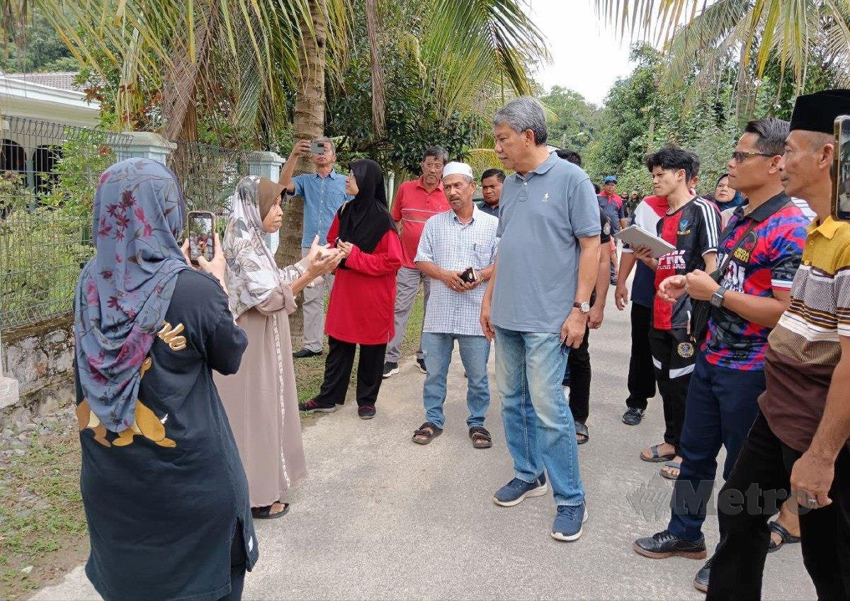 MOHAMAD (tengah) bertanyakan sesuatu kepada mangsa banjir ketika menyantuni dan menyampaikan sumbangan di Kampung Paroi. FOTO Mohd Amin Jalil.