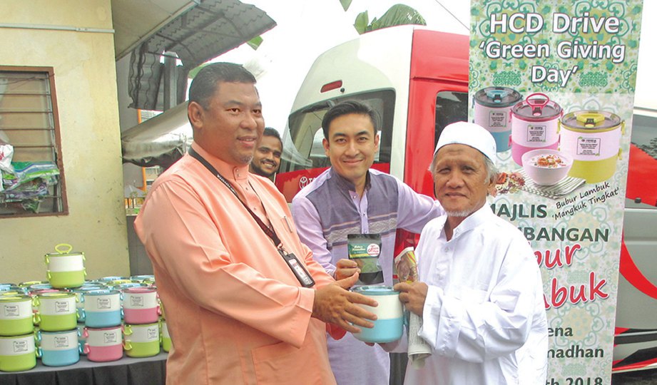 KAKITANGAN UMW Toyota Motor mengedarkan bubur lambuk kepada jemaah Masjid Jamek Raja Tun Uda.