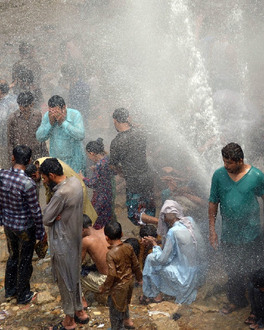 Orang ramai mengambil kesempatan mandi air saluran paip yang pecah ketika cuaca panas luar biasa melanda Karachi.  - Foto AFP 