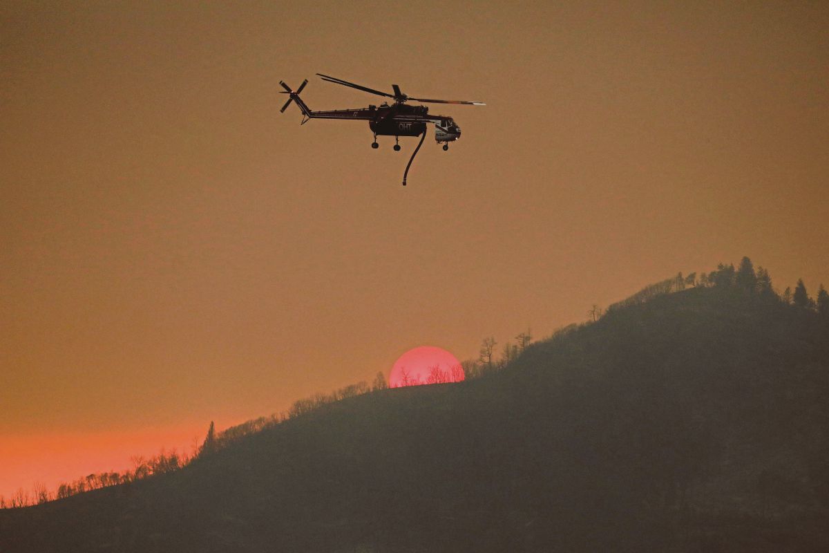 HELIKOPTER CAL Fire dilihat melalui kawasan kebakaran hutan dekat Darrah, Mariposa County, California. FOTO Reuters 