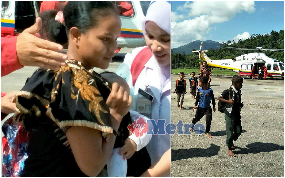 (Gambar kiri) Bayi perempuan berusia lima bulan dari Pos Gob dipangku ibunya bersama murid Orang Asli dari Pos Gob selepas penerbangan terakhir turun dari helikopter petang tadi. FOTO Ramli Ibrahim