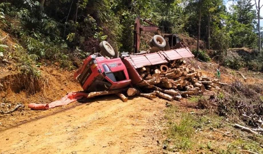 SEORANG pemandu lori maut apabila dihempap lori sarat muatan kayu getah yang terbalik di Kampung Relai, Kerambit, dekat Lipis. FOTO Ihsan IPD Lipis