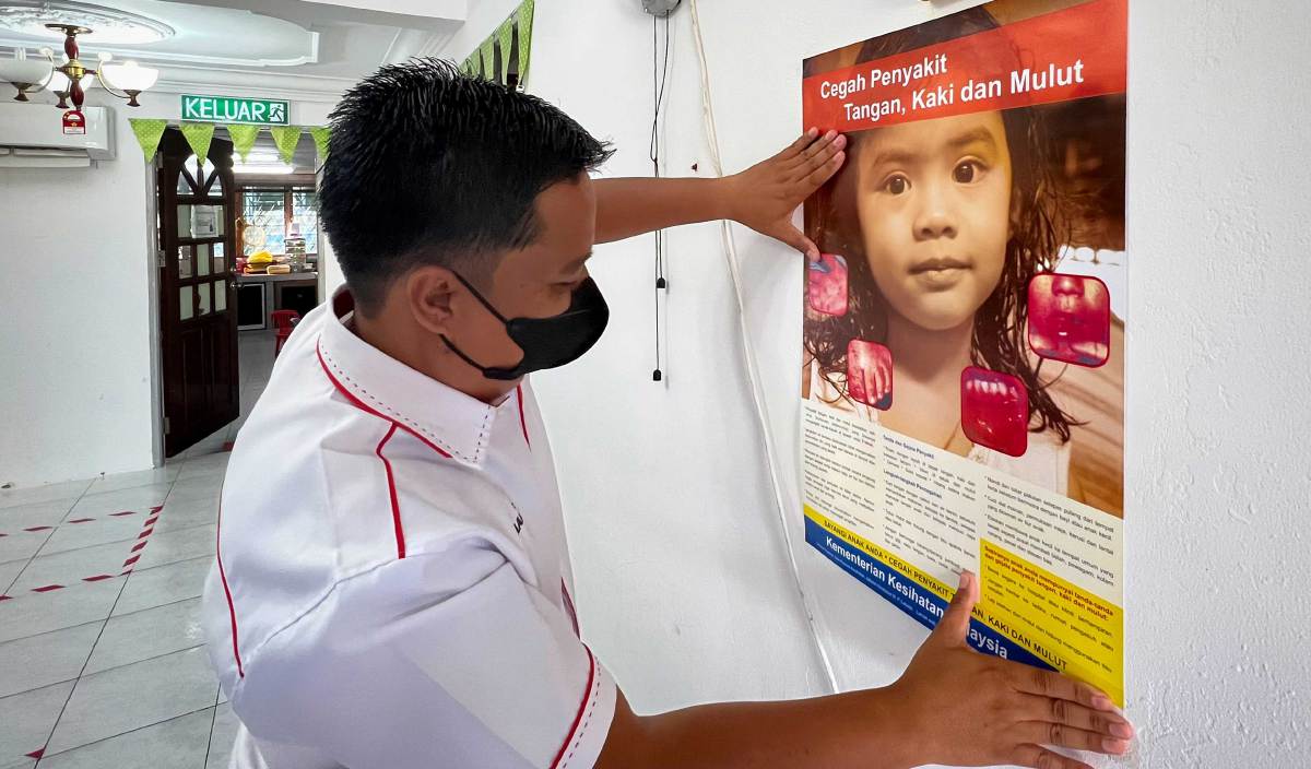 PETUGAS kesihatan menampal poster berkenaan pencegahan penyakit tangan, kaki dan mulut (HFMD) di sebuah taska dalam operasi Advokasi Pendidikan Kesihatan oleh Jabatan Kesihatan Labuan. FOTO BERNAMA