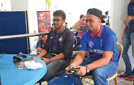 AMIRUL (kanan) bermain FIFA bersama pengunjung.