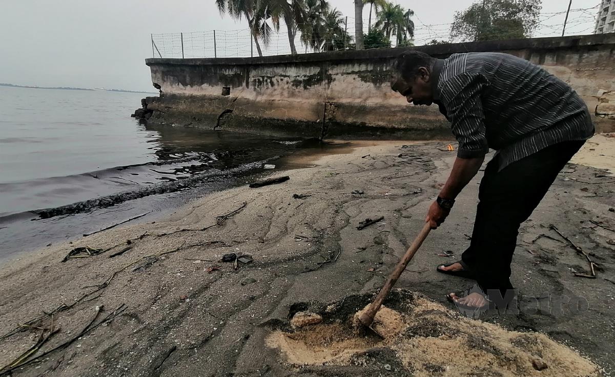 SELVARRAJU menunjukkan mendapan minyak hitam di pesisir pantai di Jalan Sultan Ahmad Shah, Georgetown, hari ini. FOTO ZUHAINY ZULKIFFLI