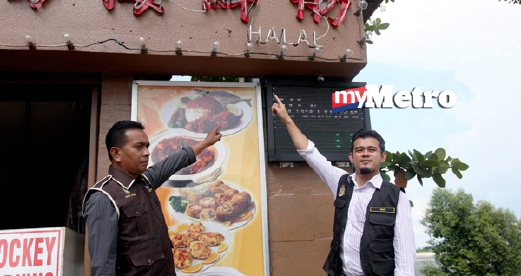 Ketua Unit Perihal Dagangan KPDNKK Ridzuan Mat Isa (kiri) dan Pembantu Hal Ehwal Islam Bahagian Pengurusan Halal, Nur Azam Che Kob menunjukkan tanda halal di luar restoran. - ZULAIKHA ZAINUZMAN