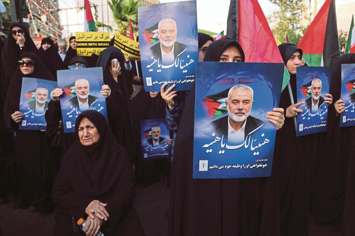 ORANG ramai memegang poster memaparkan gambar Ismail Haniyeh, semasa perhimpunan anti-Israel di Tehran, Iran, pada 31 Julai 2024. FOTO Wana/ Reuters 