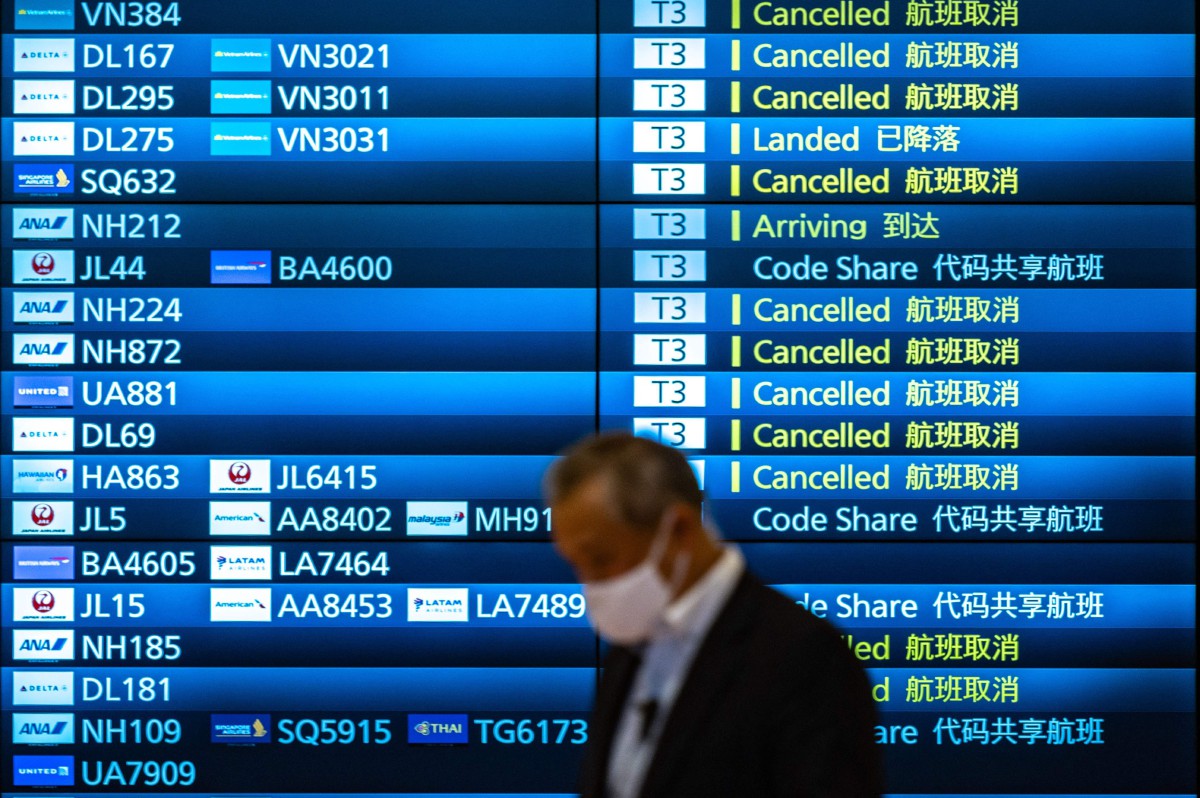 Seorang lelaki berjalan di hadapan papan ketibaan yang menunjukkan sejumlah penerbangan dibatalkan di Lapangan Terbang Antarabangsa Haneda, Tokyo. - FOTO AFP