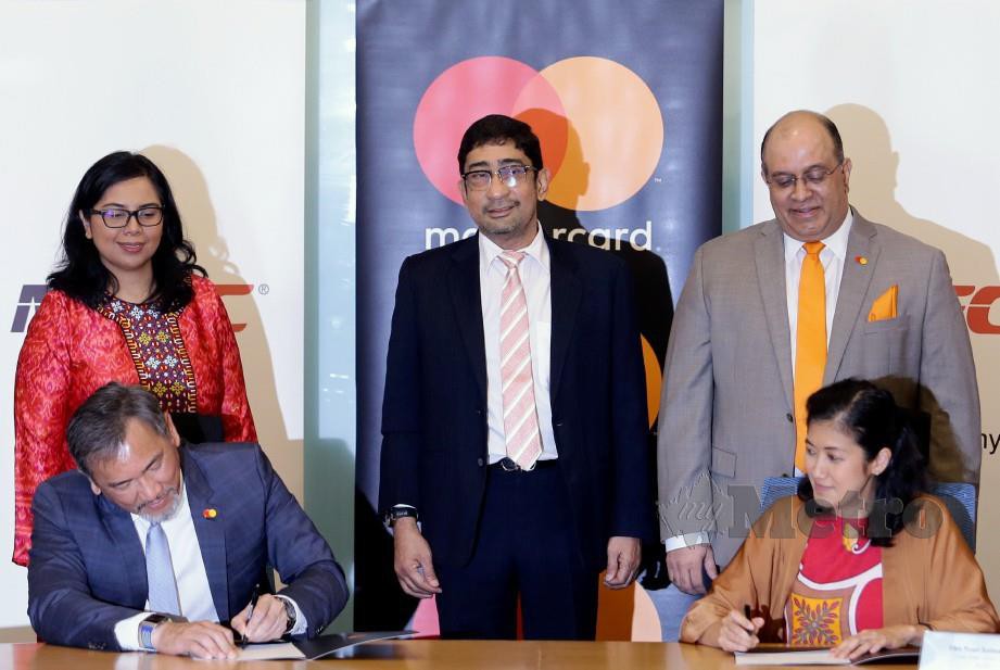 ZAHIDI  (tengah) menyaksikan Surina (duduk kanan) dan Ong  (duduk kiri) menandatangani perjanjian kerjasama antara MDEC dan Mastercard di Cyberjaya.