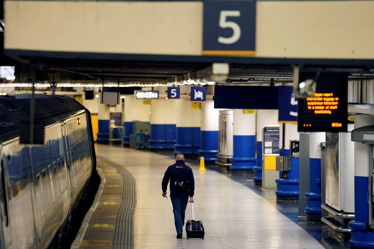 Seorang penumpang berjalan di stesen Euston, London yang lengang kerana pekerja menyertai mogok. - FOTO AP