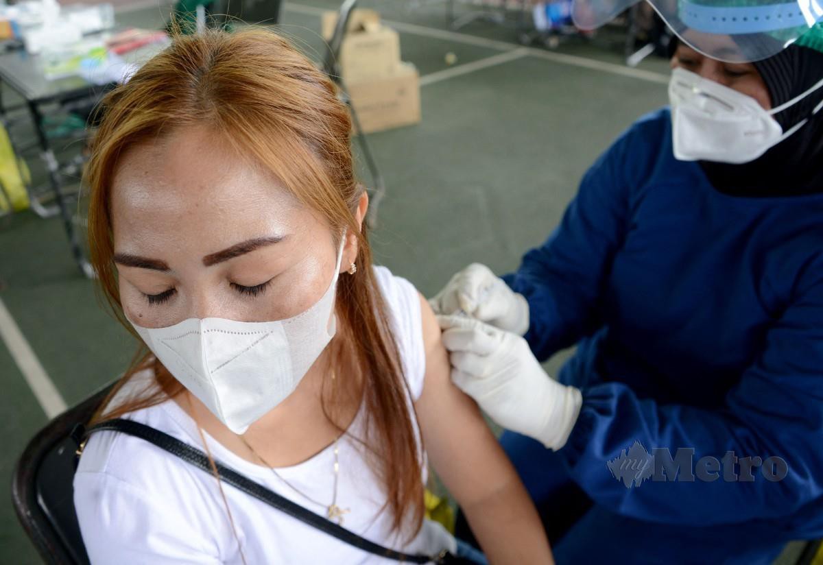 Seorang wanita mendapatkan suntikan vaksin Sinovac di hospital medan di Denpasar, Bali, Indonesia. - FOTO AFP