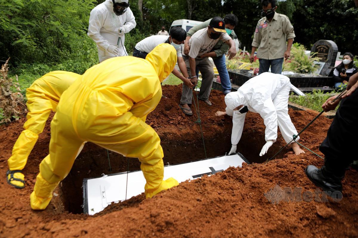Keluarga mangsa yang maut akibat Covid-19 memakai peralatan perlindungan diri (PPE) membantu mengebumikan jenazah ahli keluarga di Banda Aceh, Indonesia. - FOTO EPA