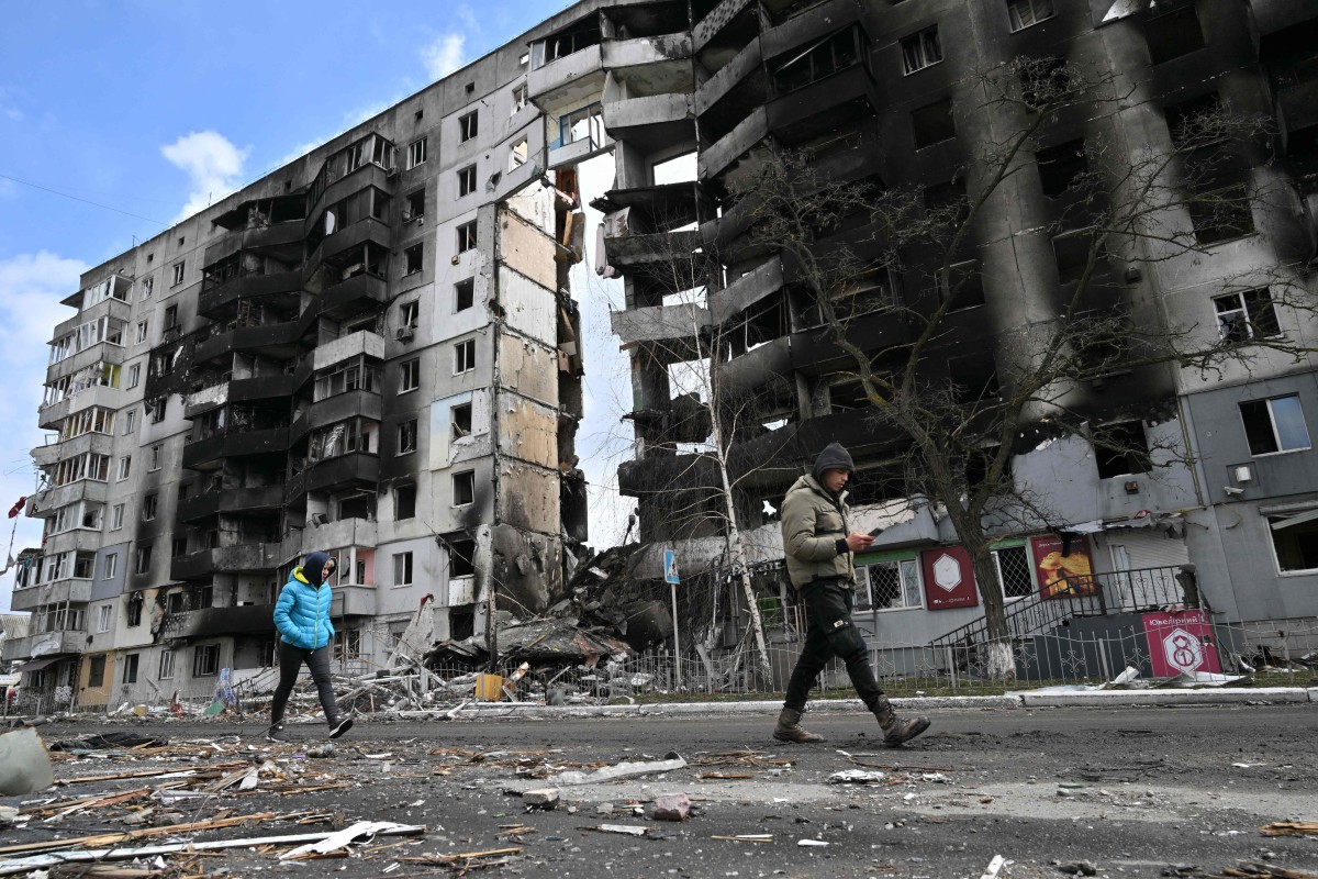 Orang awam berjalan di hadapan bangunan  yang musnah di Borodianka, Kyiv. - FOTO AFP