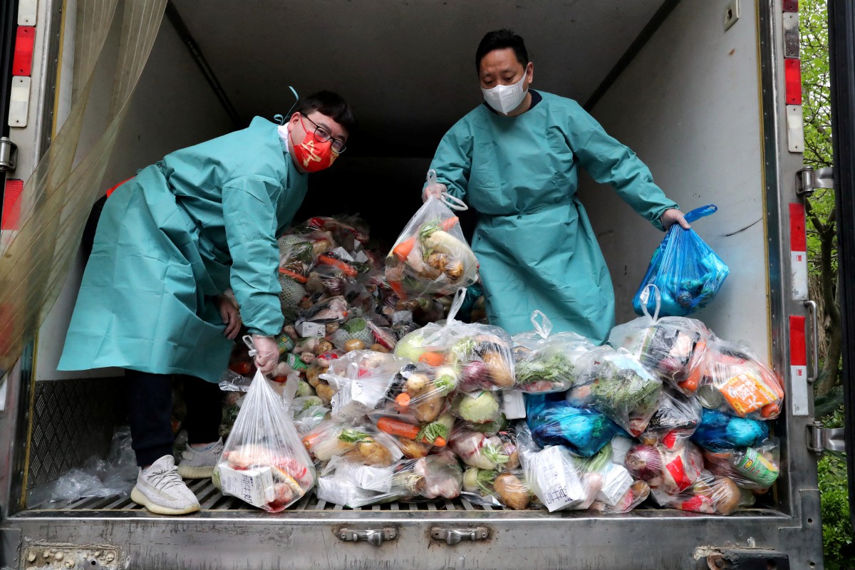 Pekerja mengenakan pakaian perlindungan untuk mengagihkan sayuran dan barangan keperluan kepada penduduk berikutan Shanghai diletakkan di bawah perintah berkurung. -  FOTO Reuters