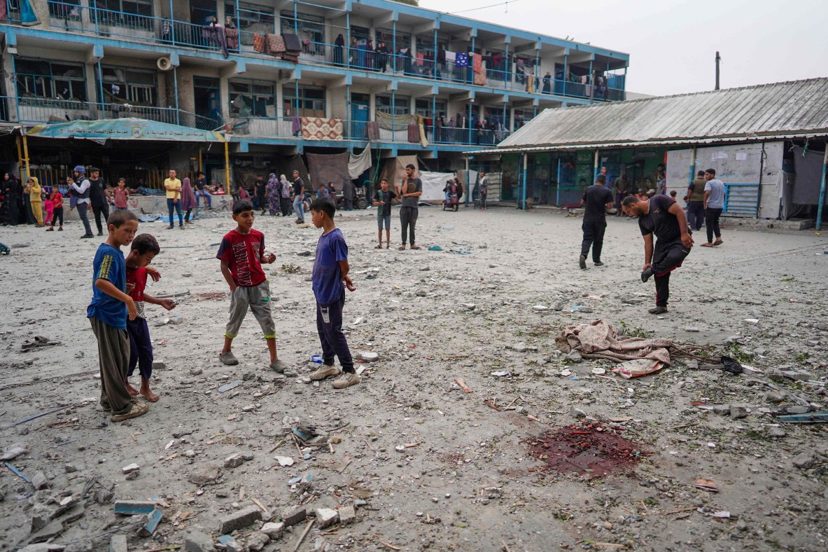 Sebahagian kanak-kanak mendekati lokasi yang mengorbankan rakan-rakan mereka di sekolah kendalian PBB di Nuseirat. - FOTO AFP