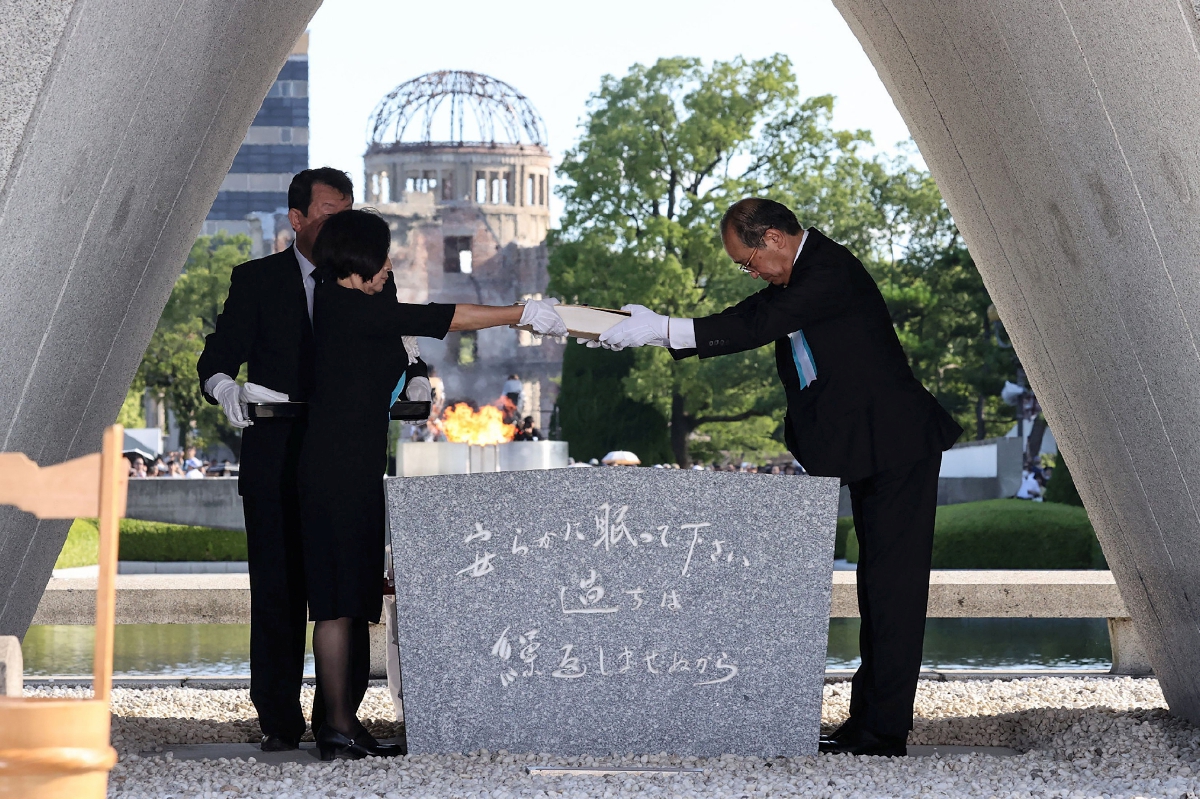 Matsui (kanan) dan wakil keluarga mangsa memegang naskhah rekod senarai nama mereka yang terkorban akibat pengeboman atom, pada upacara memperingati ulang tahun peristiwa itu di Hiroshima, hari ini. FOTO JIJI Press / AFP) / Japan OUT