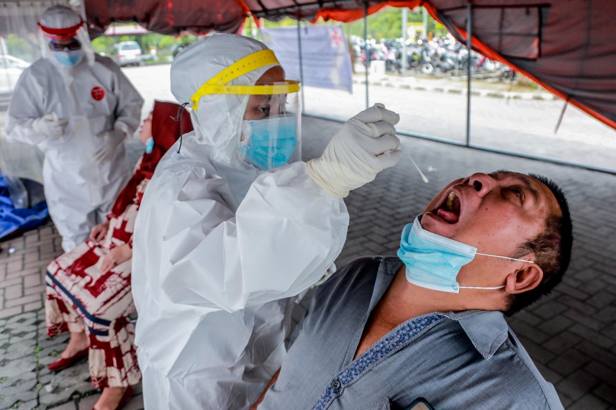 Kakitangan kesihatan mengambil sampel dari ujian calitan di Medan, Indonesia. - FOTO EPA