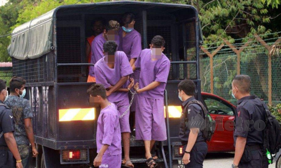 KELIMA tertuduh (memakai mask) sedang turun dari kenderaan polis ketika di bawa ke Mahkamah Magisterat Port Dickson atas kesalahan melanggar PKP. FOTO Mohd Khidir Zakaria