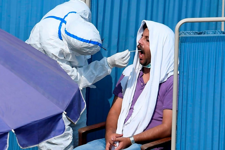KAKITANGAN perubatan melakukan ujian swab di Islamabad. Pakistan merekodkan lebih 100,000 kes jangkitan Covid-19 setakat semalam. FOTO AFP