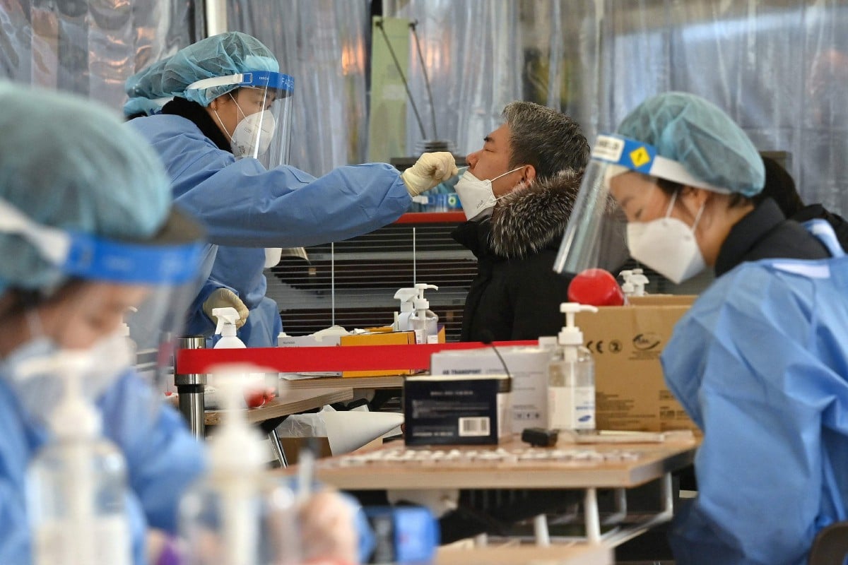 Kakitangan perubatan menjalankan ujian pengesanan Covid-19 di pusat ujian di Seoul. - FOTO AFP