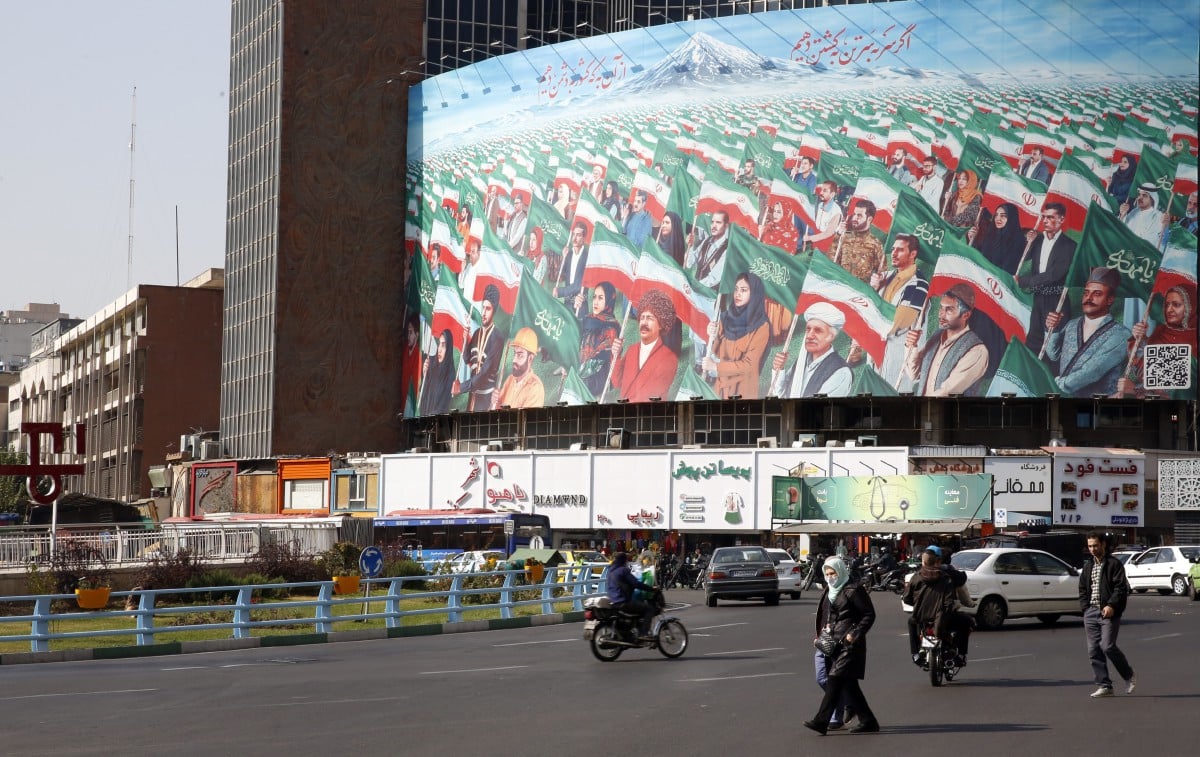 Orang awam melintasi papan iklan di Dataran Valiasr di Tehran. - FOTO EPA