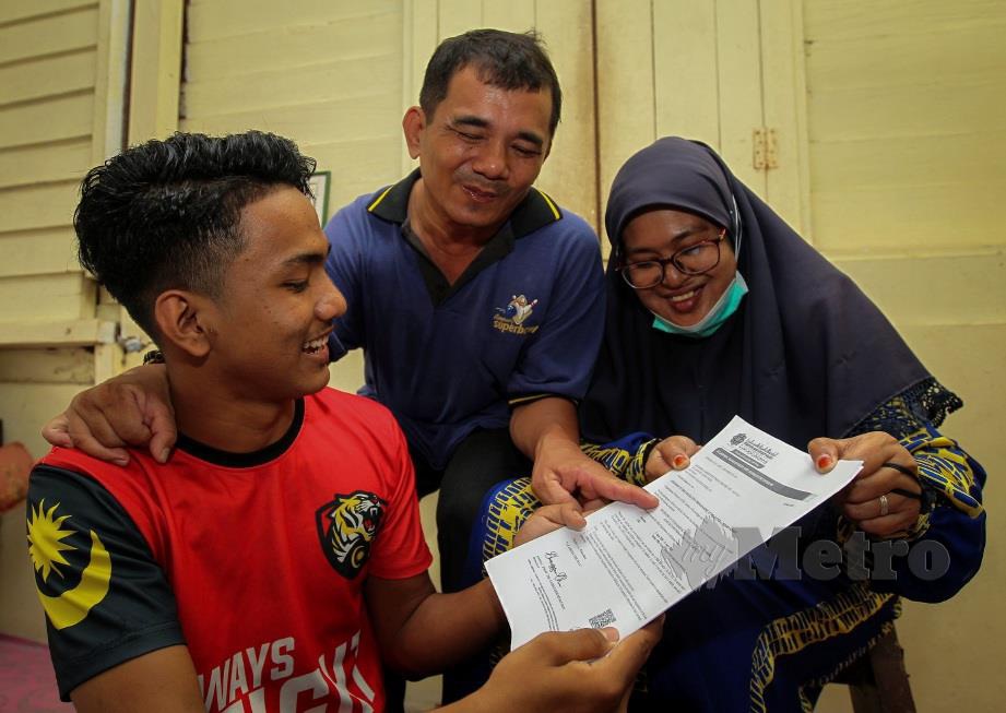 MOHSIN menunjukkan surat tawaran melanjutkan pelajaran ke Pusat Asasi UIAM Kampus Gambang Kuantan kepada kedua ibu bapa yang merupakan OKU. FOTO Azrul Edham Mohd Aminuddin